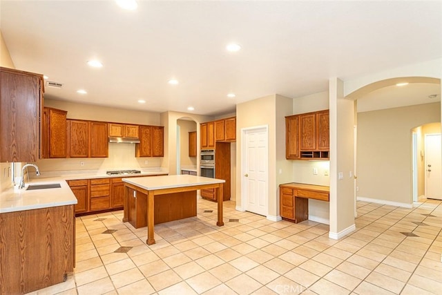 kitchen featuring a sink, a center island, recessed lighting, arched walkways, and appliances with stainless steel finishes