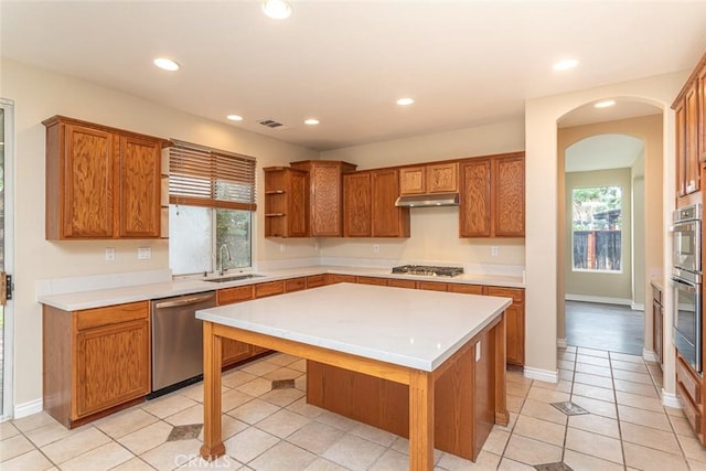 kitchen with light countertops, brown cabinets, appliances with stainless steel finishes, and a sink