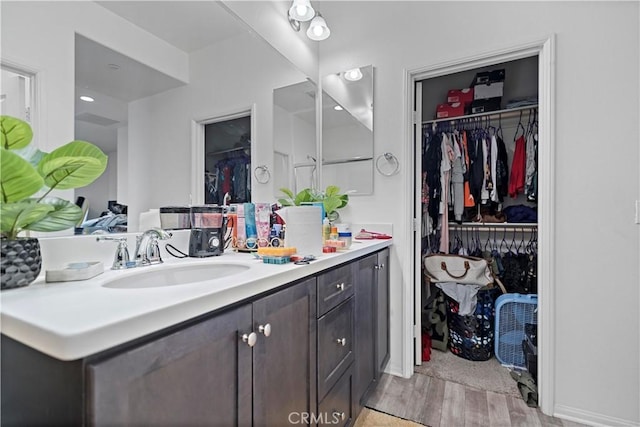 bathroom with a spacious closet, vanity, and wood finished floors