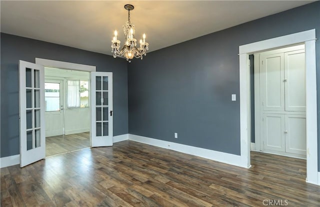 empty room featuring dark wood-style floors, a notable chandelier, french doors, and baseboards