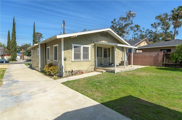 view of front facade with a front lawn, concrete driveway, fence, and a porch