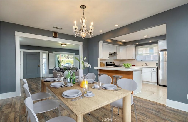 dining room featuring a chandelier, visible vents, light wood-type flooring, and baseboards