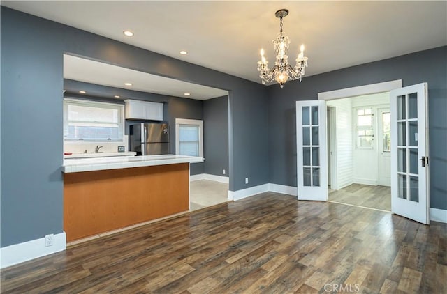 interior space with plenty of natural light, french doors, dark wood-style flooring, and a chandelier