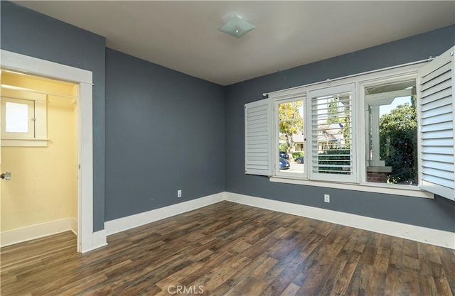 empty room with dark wood-style floors and baseboards