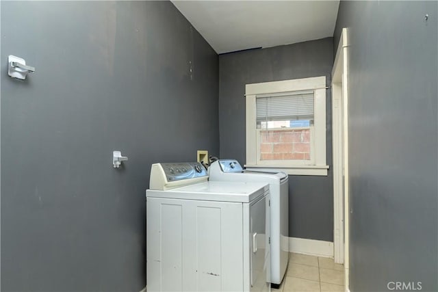 clothes washing area with light tile patterned floors, laundry area, washer and dryer, and baseboards