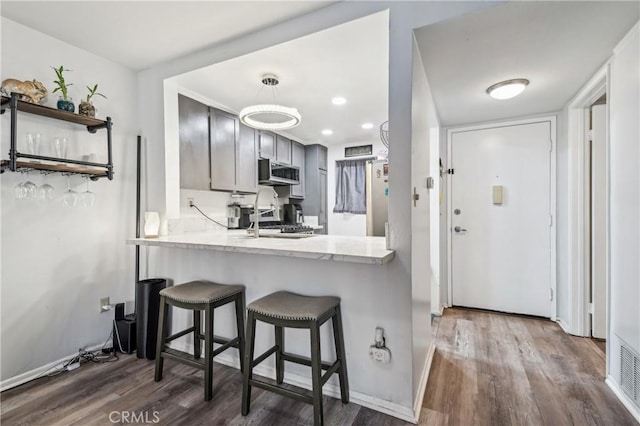 kitchen with stainless steel microwave, light countertops, dark wood-type flooring, and freestanding refrigerator