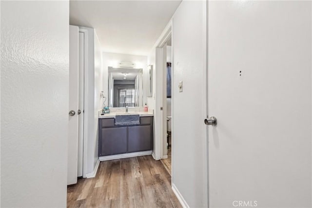 hallway with wood finished floors and a sink