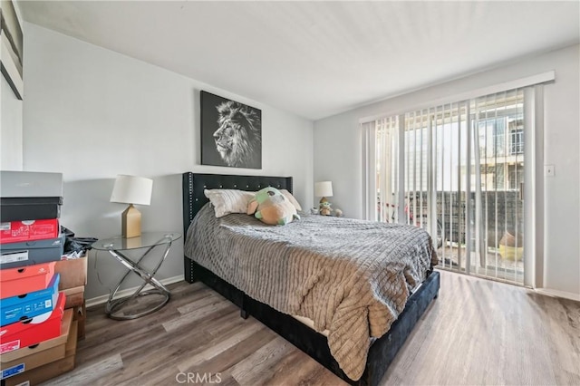 bedroom with access to outside, wood finished floors, and baseboards