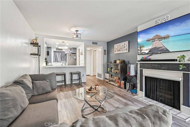 living room with visible vents, a fireplace, and wood finished floors