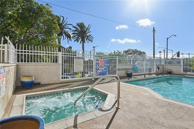 community pool with a hot tub, a patio, and fence