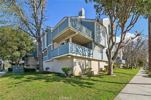 view of home's exterior featuring stucco siding, a yard, and a chimney