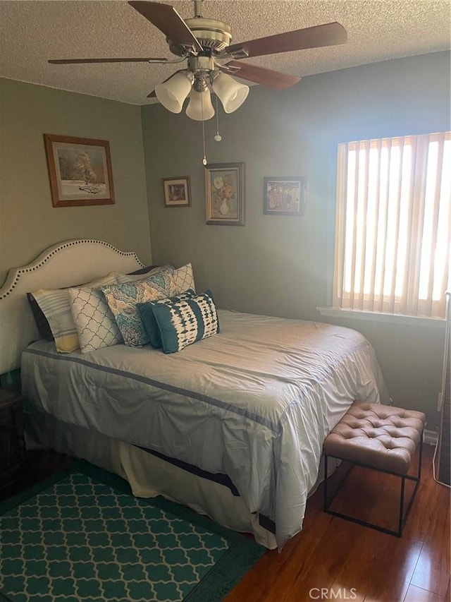 bedroom featuring a textured ceiling, a ceiling fan, and wood finished floors