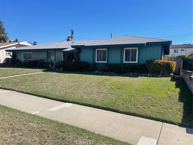 ranch-style home with a front yard and fence