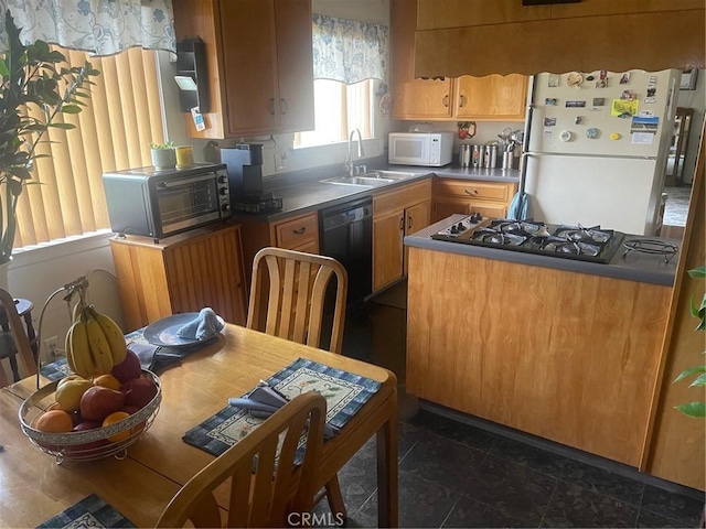 kitchen featuring a toaster, a sink, dark countertops, white appliances, and brown cabinets
