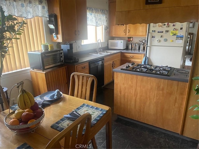 kitchen featuring brown cabinetry, white appliances, a sink, and dark countertops