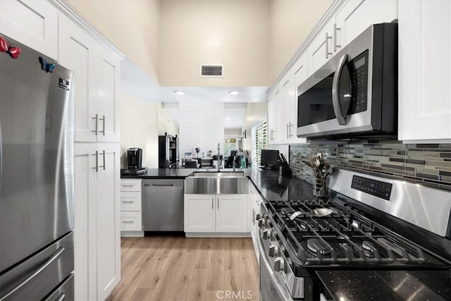 kitchen featuring visible vents, light wood-type flooring, a sink, white cabinetry, and appliances with stainless steel finishes