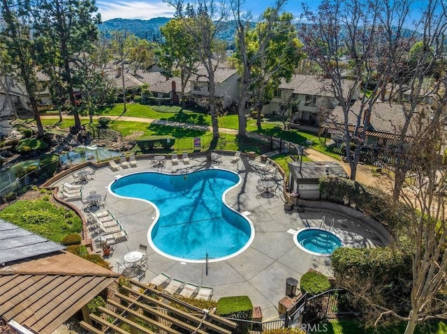 pool with a community hot tub, a yard, a patio area, and fence