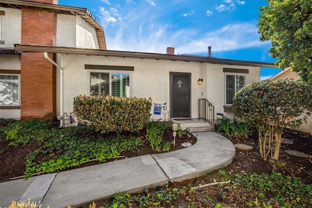 doorway to property featuring stucco siding and a chimney