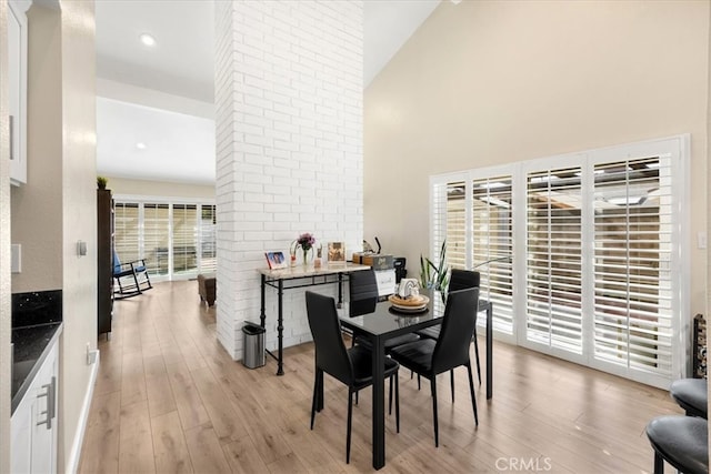 dining area featuring a high ceiling and light wood finished floors