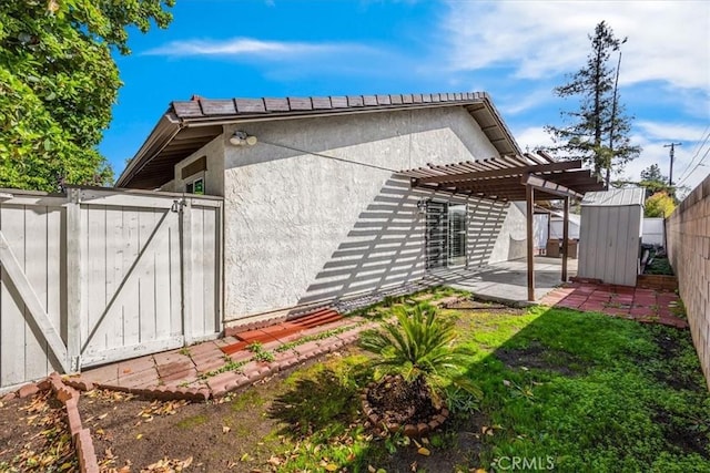 rear view of property featuring fence, a storage shed, an outbuilding, a pergola, and a patio