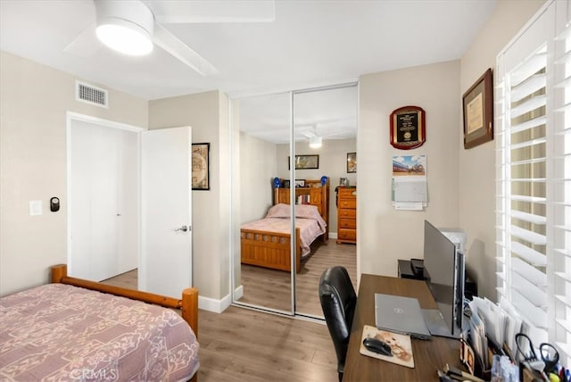 bedroom with visible vents, wood finished floors, a closet, baseboards, and ceiling fan