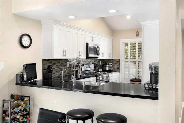 kitchen featuring stainless steel appliances, tasteful backsplash, a peninsula, and vaulted ceiling