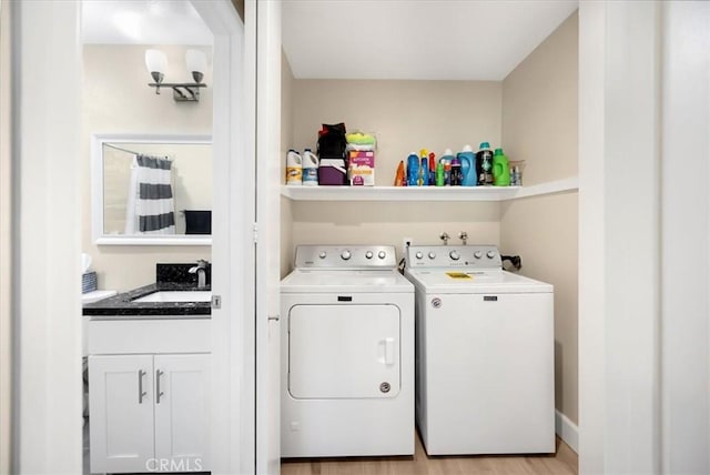 washroom with laundry area, light wood-style flooring, washing machine and clothes dryer, and a sink