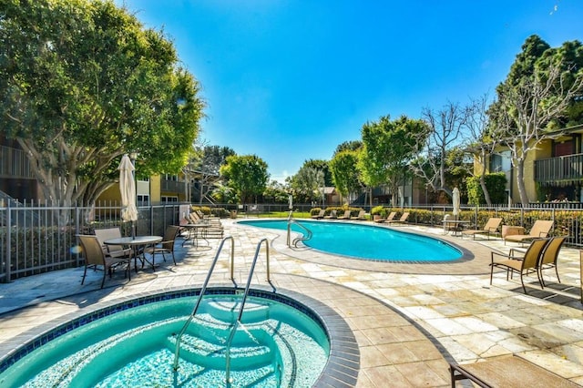 community pool featuring a patio, fence, and a hot tub