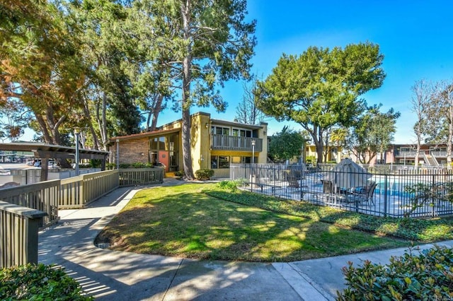 view of home's community with a yard, a pool, and fence