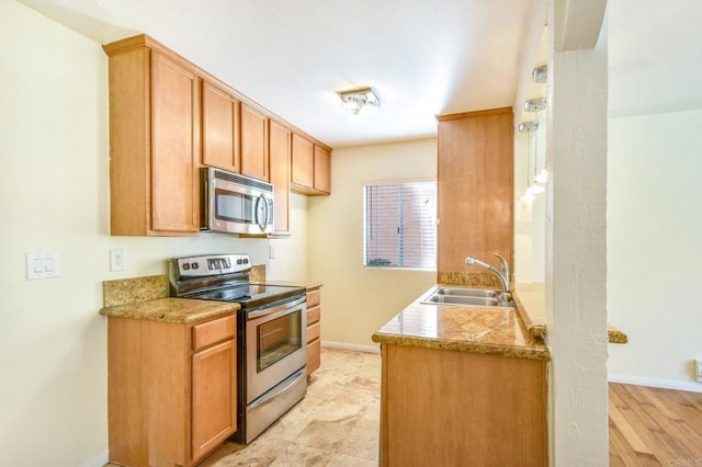 kitchen featuring a sink, light countertops, baseboards, and stainless steel appliances