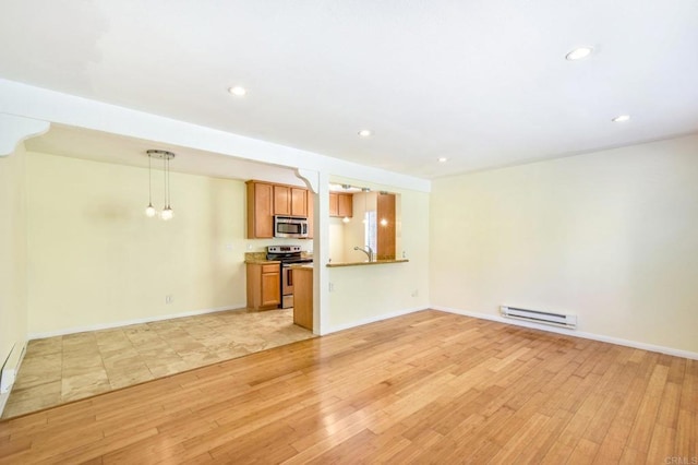 unfurnished living room with light wood finished floors, baseboard heating, recessed lighting, and baseboards