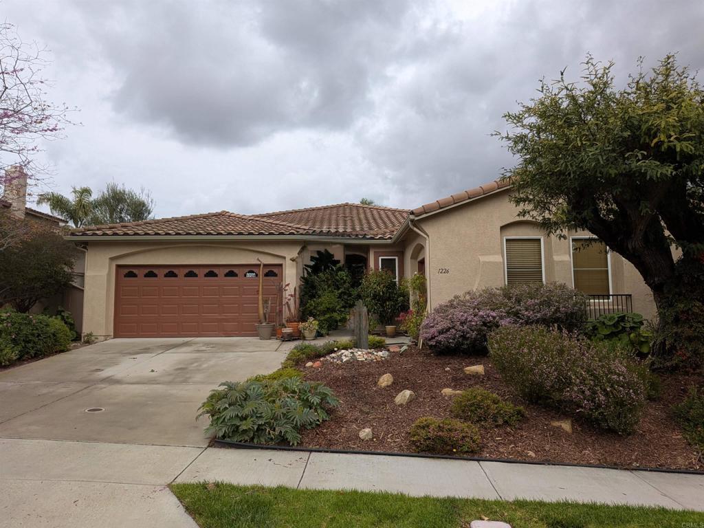 mediterranean / spanish-style house featuring concrete driveway, a tiled roof, an attached garage, and stucco siding