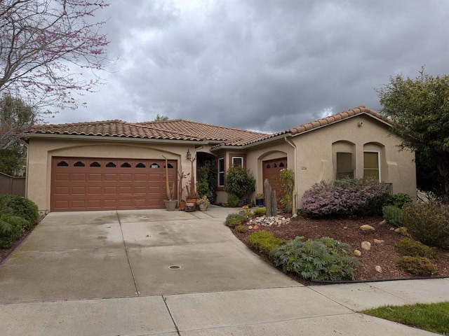 mediterranean / spanish-style house with a tiled roof, a garage, driveway, and stucco siding