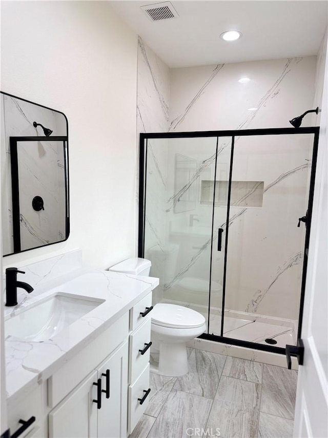 bathroom with a marble finish shower, visible vents, toilet, marble finish floor, and vanity