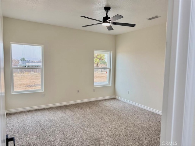 carpeted spare room with visible vents, ceiling fan, and baseboards