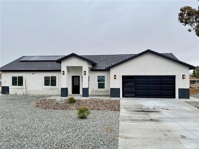 modern inspired farmhouse with driveway, an attached garage, stucco siding, a tile roof, and roof mounted solar panels