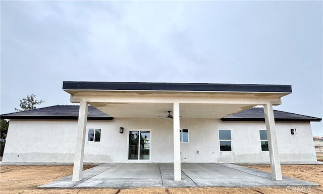 back of property with stucco siding, a patio, and a ceiling fan