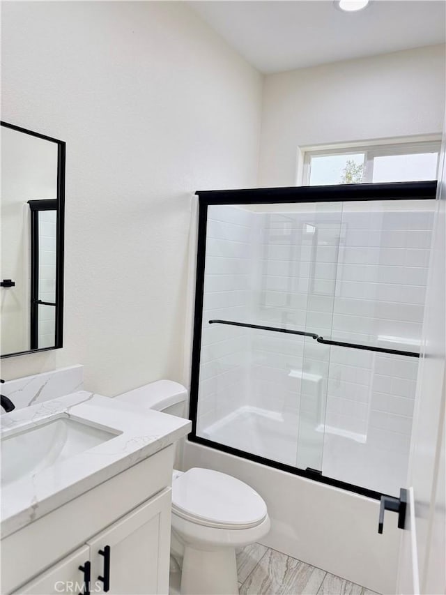 bathroom with enclosed tub / shower combo, toilet, and vanity