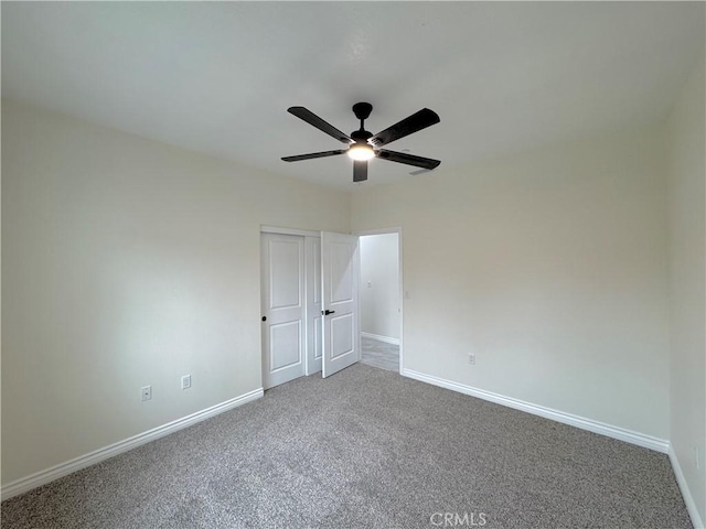 carpeted spare room with baseboards and ceiling fan