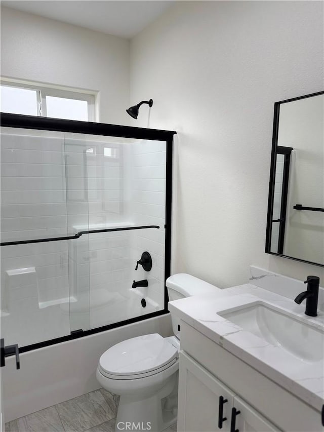 bathroom featuring enclosed tub / shower combo, toilet, and vanity