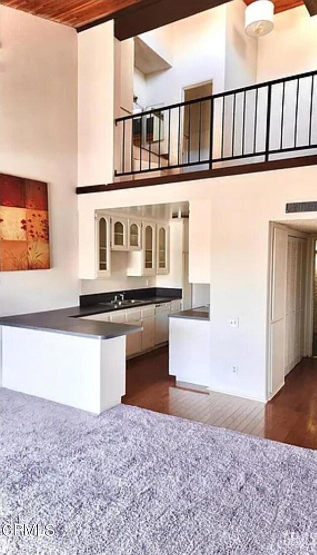 5460 White Oak Ave Unit C339, Los Angeles, CA 91316 - kitchen with dark countertops, a towering ceiling, dark wood-style floors, glass insert cabinets, and a peninsula