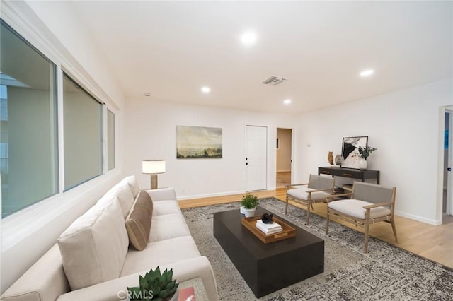 living room with recessed lighting, visible vents, baseboards, and wood finished floors