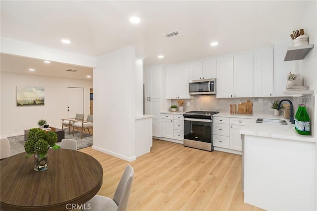 kitchen with visible vents, stainless steel appliances, light wood-type flooring, and a sink