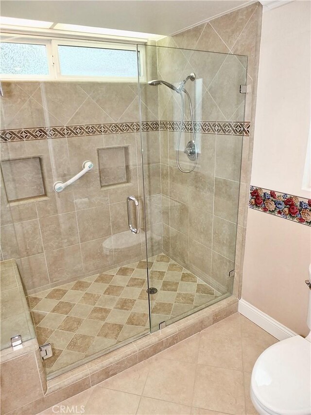 bathroom with a shower stall, toilet, and tile patterned floors