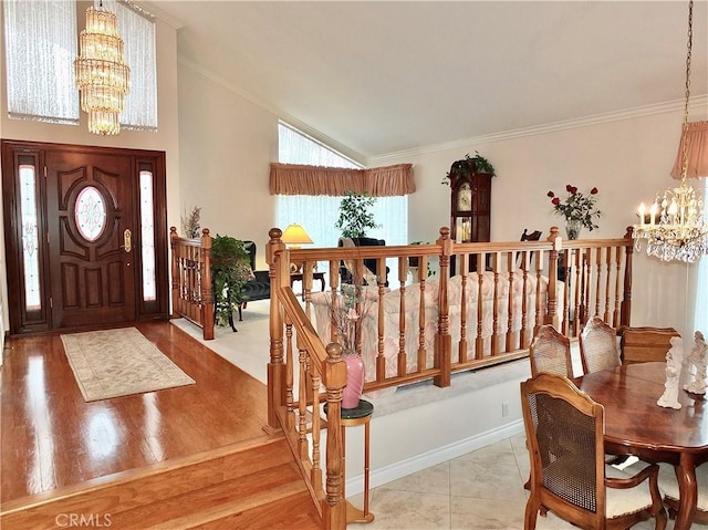 entrance foyer with a notable chandelier, wood finished floors, lofted ceiling, and ornamental molding