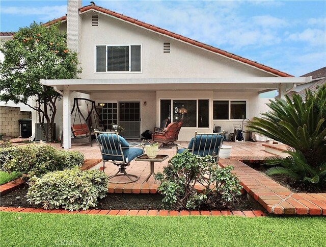 rear view of house with stucco siding and a patio area