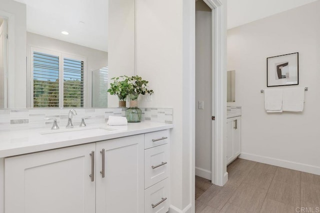 bathroom featuring baseboards, backsplash, and vanity