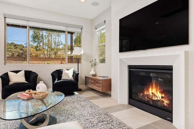 living area featuring tile patterned flooring and a glass covered fireplace