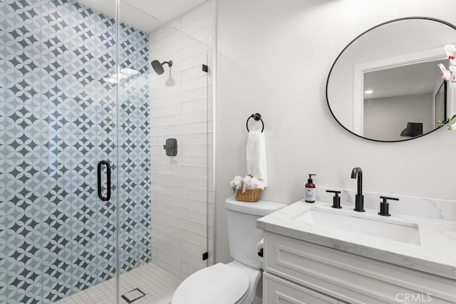 full bathroom featuring a stall shower, toilet, and vanity