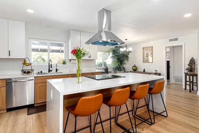 kitchen with visible vents, a sink, a kitchen breakfast bar, island range hood, and dishwasher